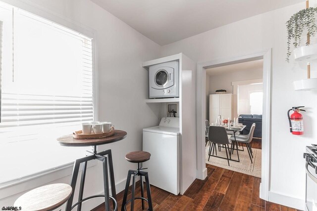 washroom with dark hardwood / wood-style flooring and stacked washer / drying machine