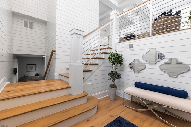 stairway featuring hardwood / wood-style floors, wood walls, and a high ceiling