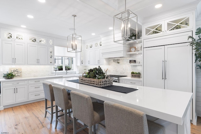 kitchen with white cabinets, a kitchen bar, a center island, and light hardwood / wood-style flooring