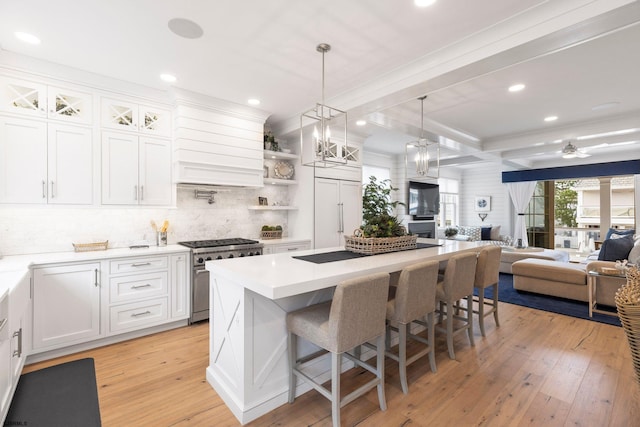 kitchen featuring premium appliances, tasteful backsplash, a kitchen bar, white cabinets, and light wood-type flooring