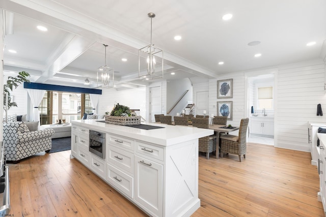 kitchen featuring pendant lighting, white cabinets, a kitchen island, beam ceiling, and light hardwood / wood-style floors