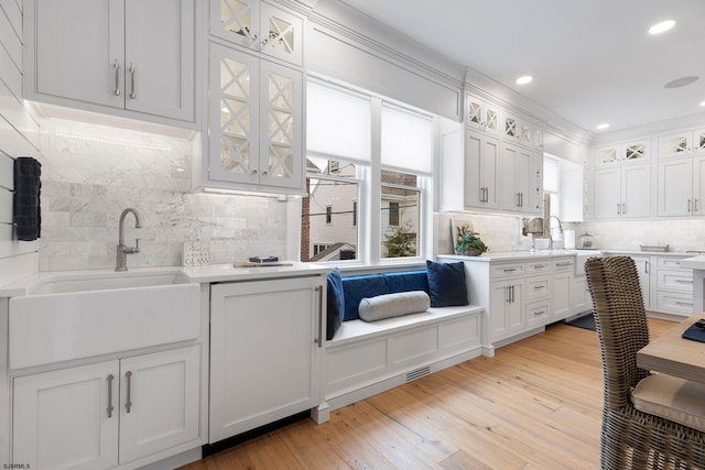 kitchen featuring white cabinets, light hardwood / wood-style floors, sink, and tasteful backsplash