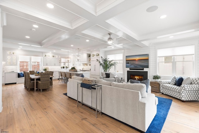 living room with ornamental molding, coffered ceiling, ceiling fan, beam ceiling, and light hardwood / wood-style floors