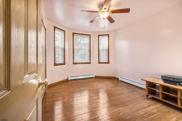 spare room with ceiling fan, wood-type flooring, and baseboard heating