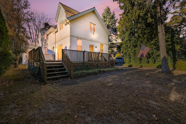 back house at dusk with a wooden deck