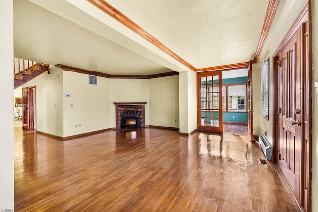 unfurnished living room with french doors, a brick fireplace, ornamental molding, a baseboard heating unit, and hardwood / wood-style floors