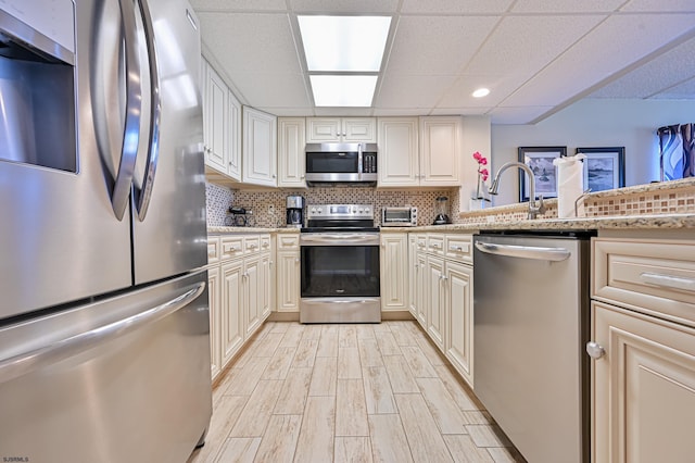 4540 W Brigantine Ave Unit N201, Brigantine, NJ 08203 - kitchen featuring stainless steel appliances, light wood-style flooring, backsplash, a drop ceiling, and light stone countertops