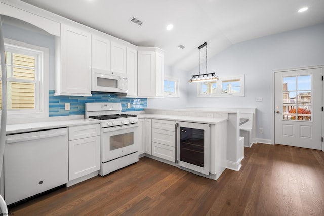 kitchen featuring white cabinets, dark hardwood / wood-style flooring, white appliances, and vaulted ceiling