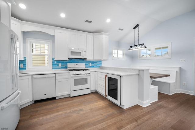 kitchen with pendant lighting, white appliances, a wealth of natural light, and dark wood-type flooring