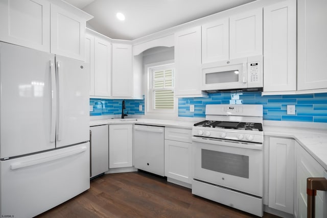 kitchen with backsplash, white appliances, sink, white cabinets, and dark hardwood / wood-style floors