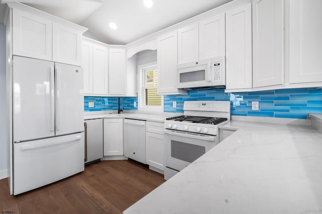 kitchen with backsplash, light stone counters, white appliances, white cabinets, and dark hardwood / wood-style floors