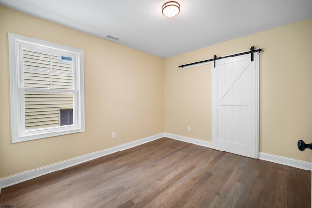 spare room featuring wood-type flooring and a barn door