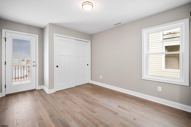 unfurnished bedroom with light hardwood / wood-style floors, access to exterior, and a closet