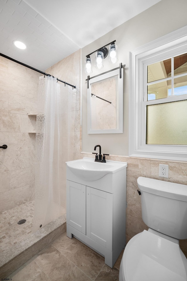 bathroom featuring curtained shower, tile patterned flooring, toilet, vanity, and tile walls