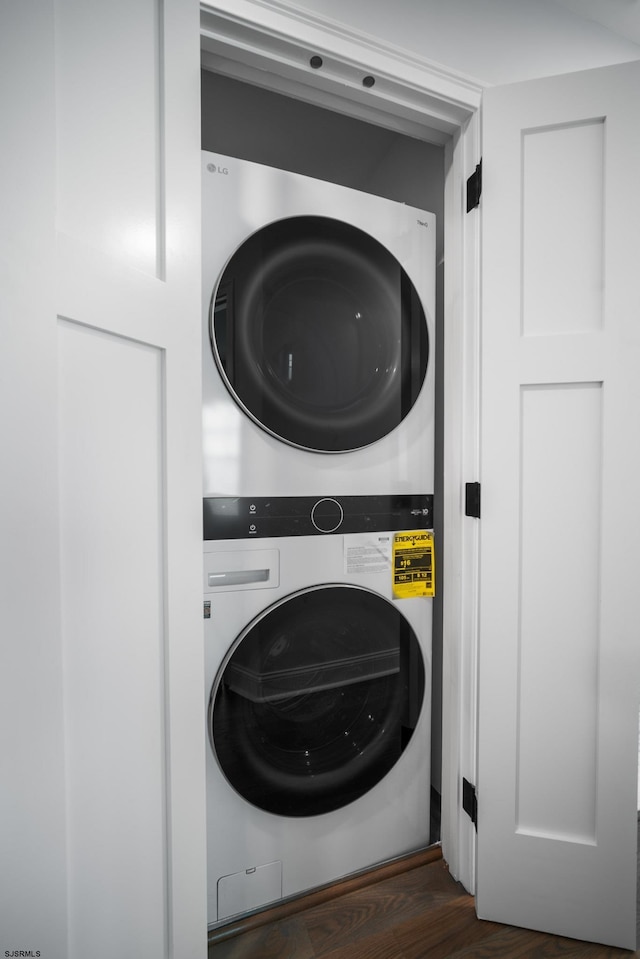 laundry room featuring dark hardwood / wood-style flooring and stacked washer / dryer