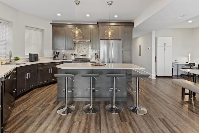 kitchen featuring pendant lighting, sink, dark hardwood / wood-style floors, dark brown cabinetry, and stainless steel appliances