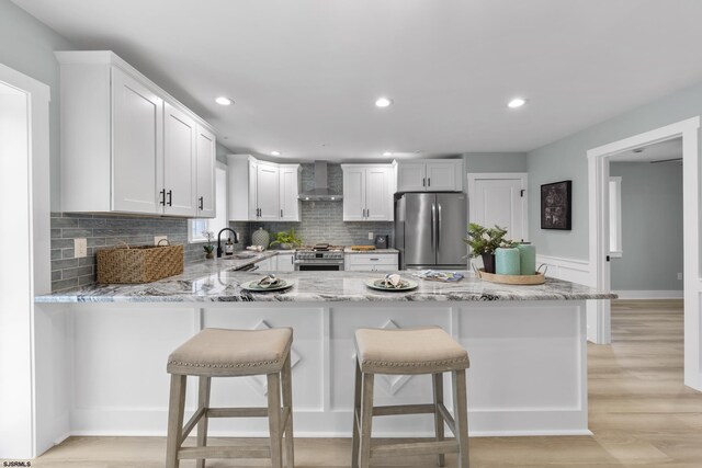 300 N Huntington, Margate, NJ 08402 - kitchen featuring stainless steel appliances, wall chimney range hood, a peninsula, decorative backsplash, and white cabinets