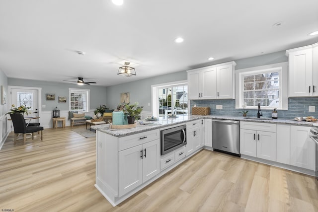 kitchen with light hardwood / wood-style flooring, white cabinets, and stainless steel appliances