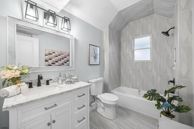 full bathroom featuring tiled shower / bath, vanity, lofted ceiling, and toilet