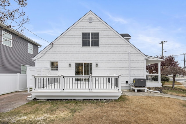 rear view of property with a lawn, central air condition unit, and a wooden deck