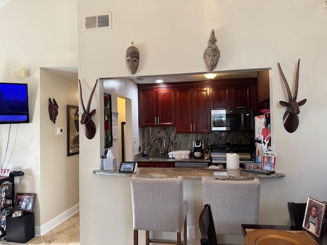 kitchen featuring kitchen peninsula, black range with electric stovetop, sink, and tasteful backsplash