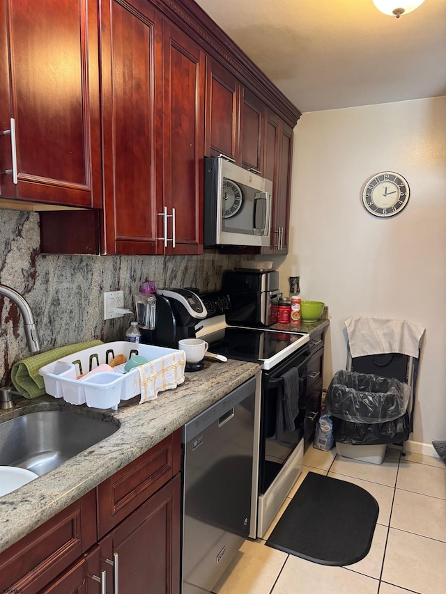 kitchen with backsplash, sink, light tile patterned flooring, light stone counters, and stainless steel appliances