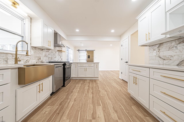 kitchen with sink, wall chimney exhaust hood, stainless steel appliances, light hardwood / wood-style flooring, and white cabinets