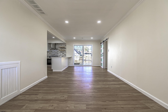 unfurnished living room with a barn door, dark hardwood / wood-style flooring, and crown molding