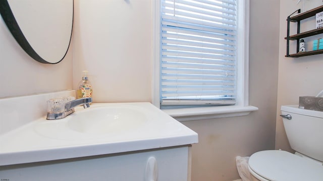 bathroom with plenty of natural light, toilet, and vanity