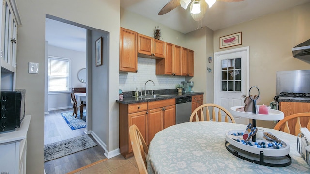 kitchen featuring ceiling fan, sink, stainless steel dishwasher, decorative backsplash, and light wood-type flooring