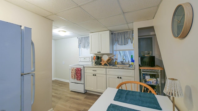 kitchen featuring white cabinetry, light wood-type flooring, white appliances, and sink