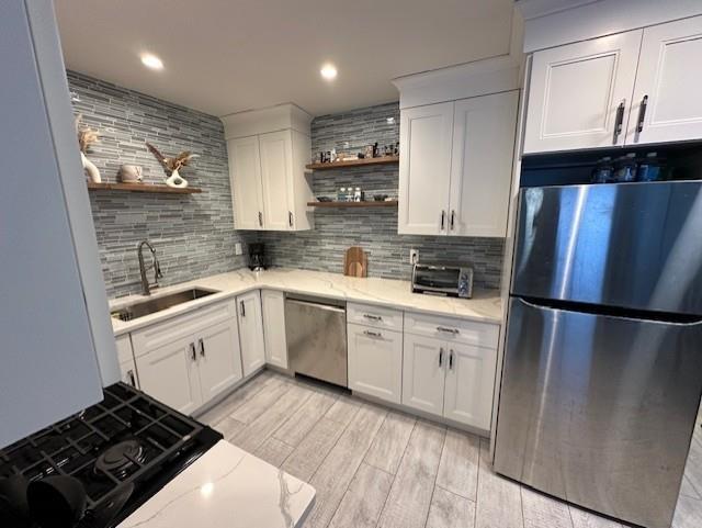 kitchen featuring white cabinets, appliances with stainless steel finishes, backsplash, and sink