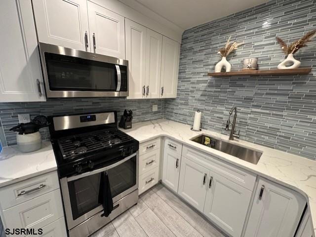 kitchen with appliances with stainless steel finishes, backsplash, white cabinetry, and sink