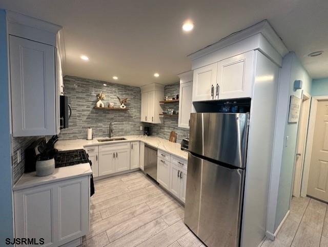 kitchen with decorative backsplash, stainless steel appliances, sink, light hardwood / wood-style flooring, and white cabinetry