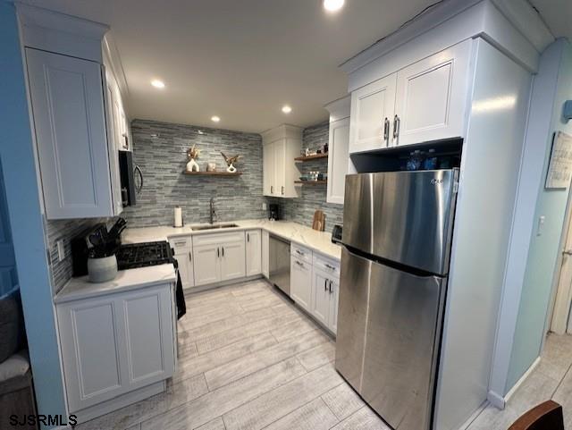 kitchen featuring tasteful backsplash, white cabinetry, sink, and stainless steel appliances