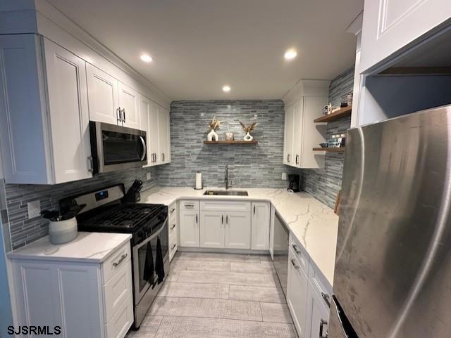 kitchen with white cabinets, decorative backsplash, stainless steel appliances, and sink