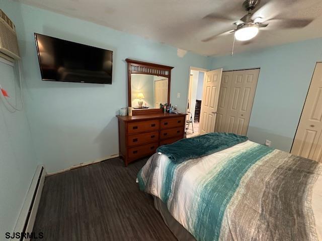 bedroom featuring ceiling fan, dark hardwood / wood-style floors, baseboard heating, and a closet