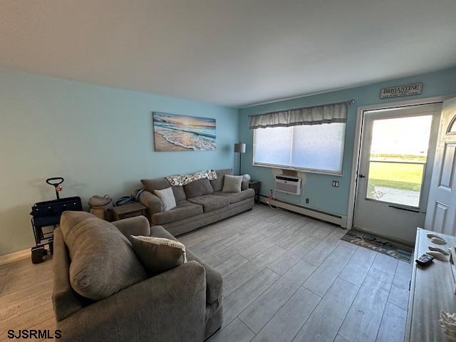 living room featuring light hardwood / wood-style flooring, a healthy amount of sunlight, and a baseboard radiator