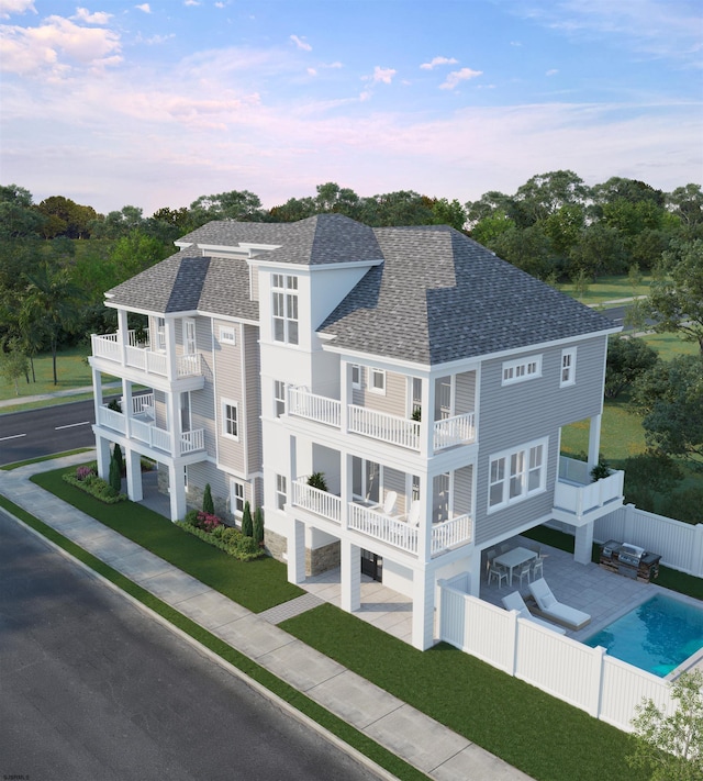 rear view of house featuring a lawn, a patio area, a balcony, and a fenced in pool