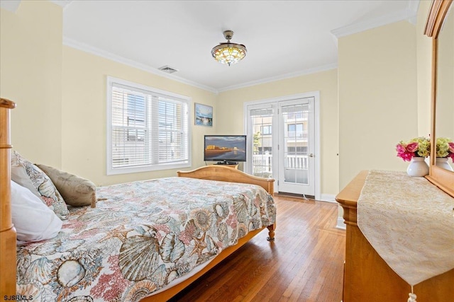 bedroom featuring hardwood / wood-style flooring, crown molding, and multiple windows