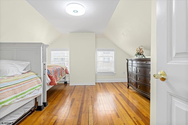 bedroom featuring multiple windows, light hardwood / wood-style floors, and lofted ceiling