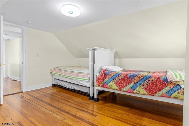 bedroom with hardwood / wood-style floors and vaulted ceiling