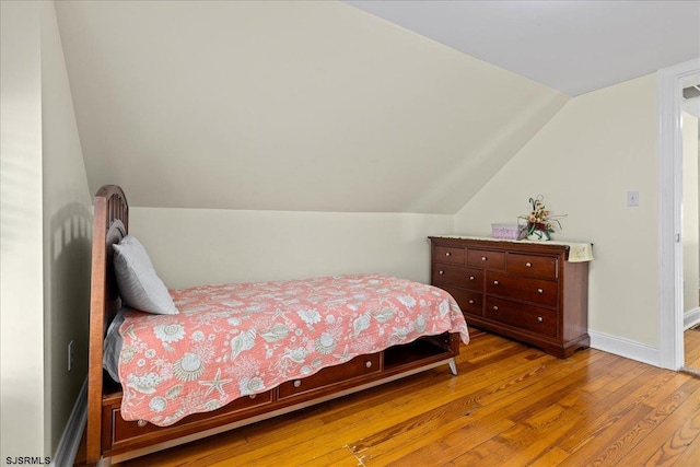 bedroom with hardwood / wood-style floors and lofted ceiling