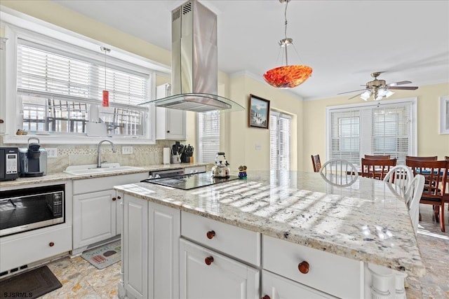 kitchen featuring decorative backsplash, black electric stovetop, island range hood, white cabinetry, and stainless steel microwave