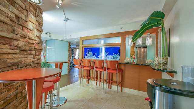 bar with light tile patterned floors and stainless steel refrigerator