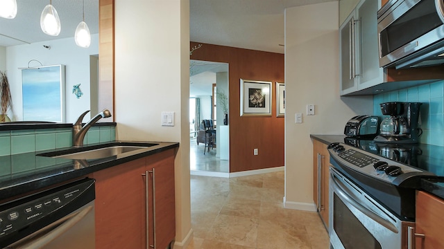 kitchen with tasteful backsplash, sink, pendant lighting, and appliances with stainless steel finishes