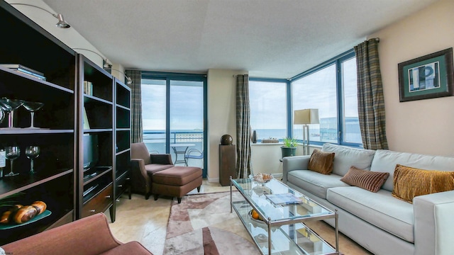 living room with expansive windows, a water view, a healthy amount of sunlight, and a textured ceiling