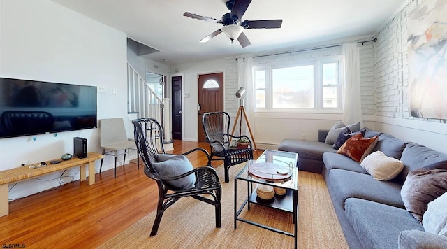 living room featuring ceiling fan, brick wall, and light wood-type flooring