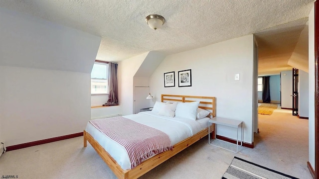 carpeted bedroom with a textured ceiling and vaulted ceiling