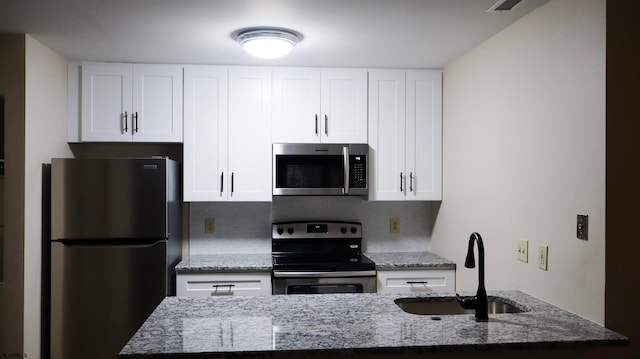 kitchen featuring backsplash, light stone counters, stainless steel appliances, sink, and white cabinetry